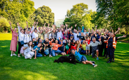 A group of about 50 volunteers group together and cheer for the camera.